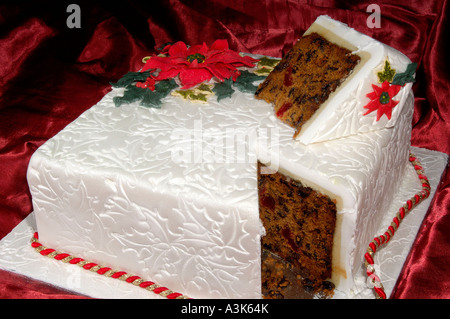 Joliment décorées de Noël gâteau glacé aux fruits avec des feuilles de houx en relief et red poinsettia fleurs faites à partir de la cerise Banque D'Images