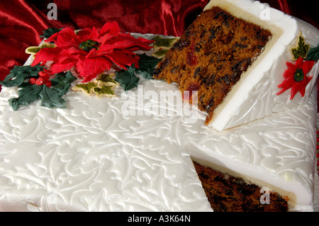 Joliment décorées de Noël gâteau glacé aux fruits avec des feuilles de houx en relief et red poinsettia fleurs faites à partir de la cerise Banque D'Images