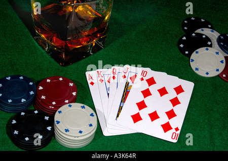Cartes de poker montrant un flush royal avec des jetons de casino et un verre de whisky sur les rochers tout de feutrine verte table à cartes Banque D'Images