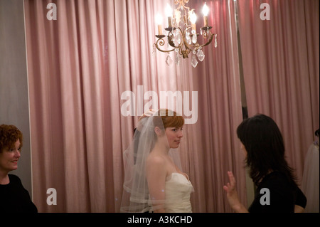 Une jeune femme se regarde dans un miroir car elle essaie sur une robe de mariée blanche dans un magasin à New York USA Janvier 2006 Banque D'Images