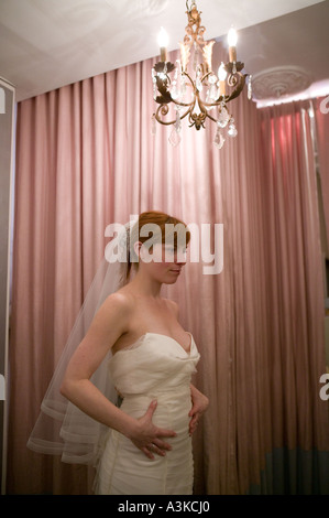 Une jeune femme se regarde dans un miroir car elle essaie sur une robe de mariée blanche dans un magasin à New York USA Janvier 2006 Banque D'Images