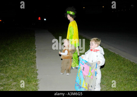 Les jeunes enfants autour du porte à porte dans leur quartier pour Halloween Banque D'Images