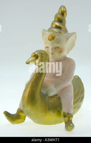 Figurine pixie antique dans un chapeau d'or assis sur une oie d'or Banque D'Images