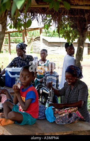 Femme ghanéenne couturière et la famille à l'aide de la machine à coudre à main l'Afrique de l'Ouest Banque D'Images