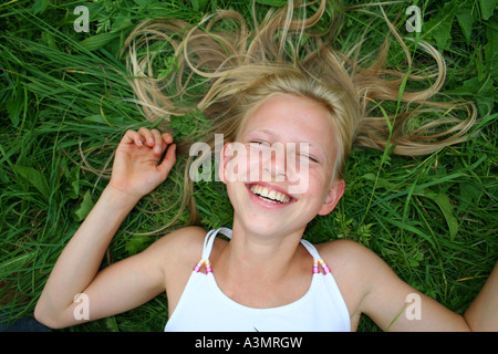 Jeune fille blonde rire dans l'herbe Banque D'Images