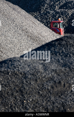 Cabine d'un camion rouge qui se trouve derrière l'inventaire des piles de gravier prêtes à être transportées vers les chantiers de construction , Finlande Banque D'Images