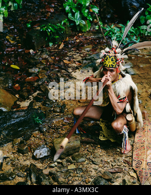 Un tribesman nomade de la forêt de Penan démontre l'utilisation d'un tuyau de soufflage, Sarawak, Bornéo, Malaisie. Banque D'Images
