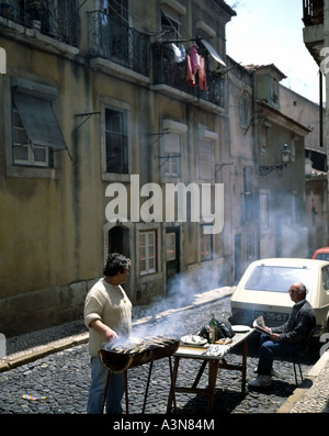 MAN GRILLING SARDINES SUR LA RUE DANS LE QUARTIER DE BICA LISBONNE PORTUGAL Banque D'Images