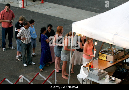 Les gens de beaucoup de races mixtes line up ou d'une file d'attente pour takeawy la nourriture au lieu d'une piscine en plein air Banque D'Images