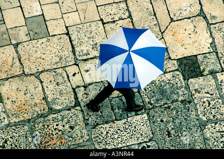 Homme marchant avec parapluie bleu et blanc sur lapiez vue aérienne Banque D'Images