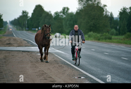 Agriculteur sur une bicyclette menant son cheval, Lituanie Banque D'Images