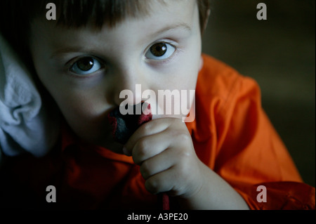 Young caucasian boy in shirt orange sucking thumb Banque D'Images