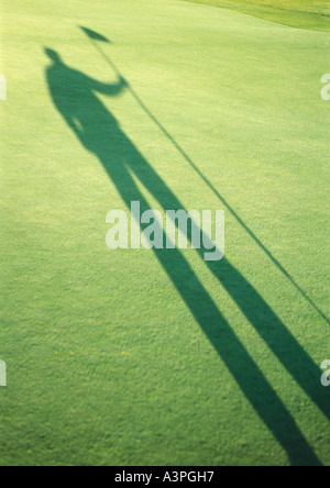 Ombre de golfer holding golf flag Banque D'Images