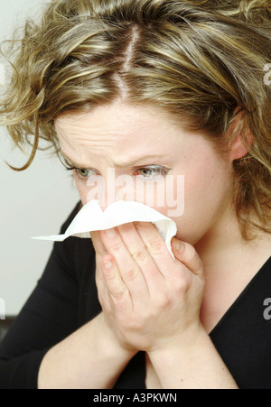 Young woman blowing her nose Banque D'Images