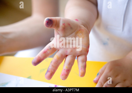 Petite fille avec les mains dans la peinture Banque D'Images