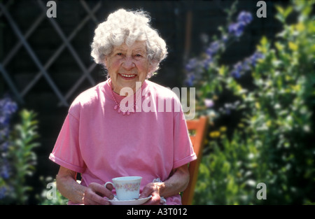 Quatre-vingt-dix ans anglaise ayant une tasse de thé dans son jardin Banque D'Images