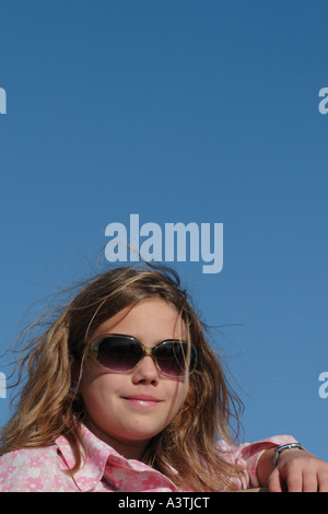 Jeune fille âgée de 12 ans portant des lunettes de soleil et chemisier rose Banque D'Images