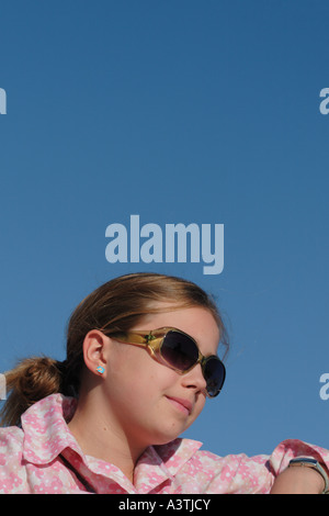 Jeune fille âgée de 12 ans portant des lunettes de soleil et chemisier rose Banque D'Images