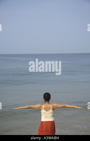 Les femmes sur l'exercice de détente de vacances bénéficiant d'asanas du yoga debout sur la plage mer sable soleil Banque D'Images