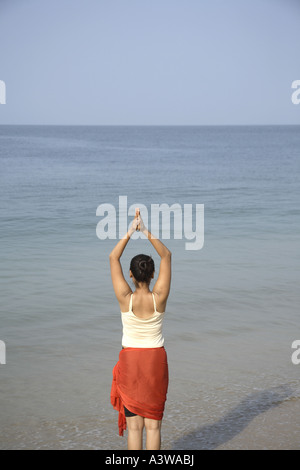 Les femmes sur l'exercice de détente de vacances bénéficiant d'asanas du yoga debout sur la plage mer sable soleil Banque D'Images