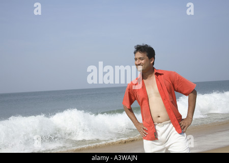 Homme debout en toute confiance avec les mains sur les hanches montrant la confiance sur la plage de la mer de sable propre Banque D'Images