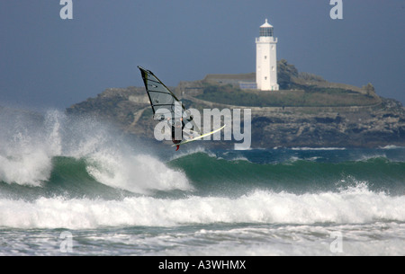 Windsurfer sautant une vague près de phare de Godrevy, Cornwall, UK Banque D'Images