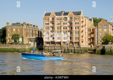 Lancement du moteur de Tamise passant Olivers Wharf quai entrepôt converti en maisons riverside Tower Hamlets Wapping East London England UK Banque D'Images