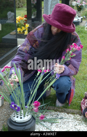 Woman arranging flowers à une tombe, UK Banque D'Images