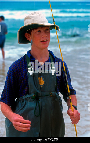 Les jeunes dans les pataugeoires pantalon avec canne à pêche surf Fraser Island, Queensland, Australie Banque D'Images