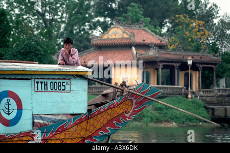 Passeur sur la rivière parfumée à Hué au Vietnam. Temple dans l'arrière-plan. Banque D'Images