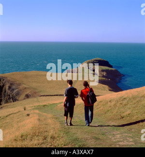 Vue arrière de l'arrière de deux jeunes hommes promeneurs marchant sur le sentier du littoral du pays de Galles à Ynys Lochtyn Llangranog dans Ceredigion, West Wales UK KATHY DEWITT Banque D'Images