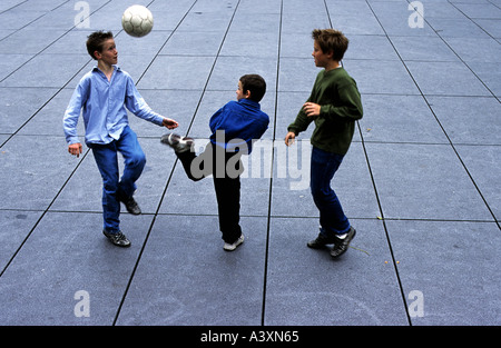 Groupe d'amis jouant au football dans la rue à Paris, France. Banque D'Images