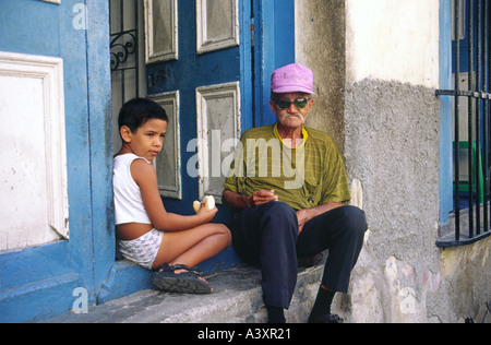 L'homme et jeune garçon assis à leur porte avant dans la vieille Havane Cuba Banque D'Images