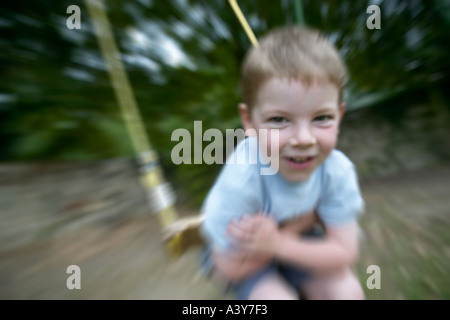 Young caucasian boy joue en plein air sur une balançoire Banque D'Images