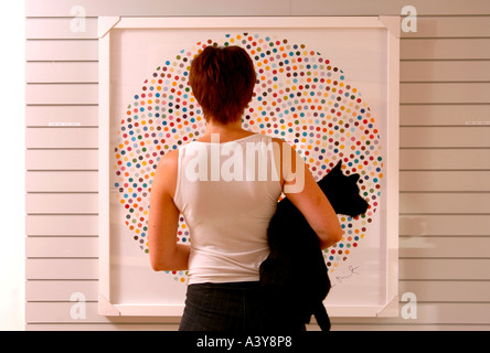 Une femme de l'affichage d'un Damien HIRST DOT PAINTING INTITULÉ VALIUM DANS UNE GALERIE D'ART D'EYESTORM Banque D'Images