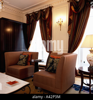 Fauteuils de coin et lourds rideaux en soie marron sur de grandes fenêtres dans le salon Maison Banque D'Images