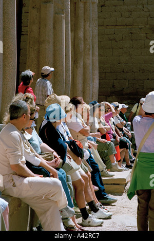 Les touristes se reposer pendant l'écoute de leur guide dans le temple de Louxor en Égypte Banque D'Images