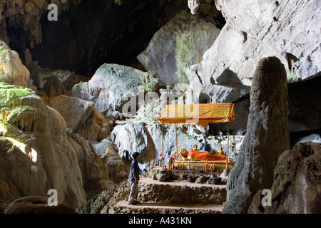 Séjour touristique en face de Bouddha de bronze inclinables à l'intérieur de la grotte Phu Kham Vang Vieng Laos Banque D'Images