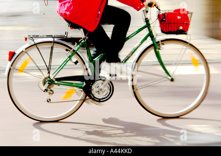 Vue latérale floue d’un vélo en mouvement, se concentrant sur les jambes du cycliste pédalant, avec un arrière-plan flou Banque D'Images