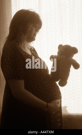 Les jeunes femmes enceintes en bonne santé Tenant son enfant à naître de nounours. Banque D'Images