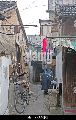 Chine SHANGHAI ruelle typique dans la vieille ville de Shanghai avec des vélos et de séchage des vêtements et des oiseaux en cage Banque D'Images