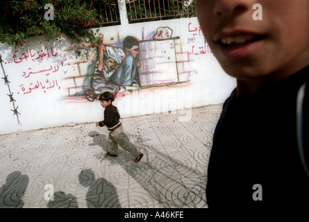 Mohammed al dourra gaza murale enfants jouer près d'une peinture murale dans la ville de Gaza représentant la mort de 12 ans, Mohammed al dourra 5 décembre 2000 Tué par l'armée israélienne lors d'un affrontement à la traversée de Netzarim dans la bande de Gaza pendant la deuxième intifada gaza ville de Gaza 5 12 00 Les enfants jouent près d'une peinture murale représentant la mort de 12 ans, Mohammed al dourra mortellement blessé par l'armée israélienne lors d'un affrontement à la traversée de Netzarim à Gaza Banque D'Images