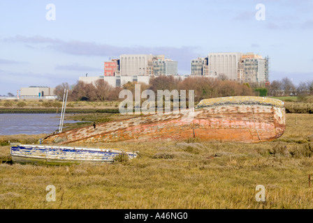 La rivière Blackwater a abandonné la coque du bateau sur le paysage au bord de la rivière avec les bâtiments de la centrale nucléaire de Bradwell Bradwell Waterside Essex Coast Angleterre Royaume-Uni Banque D'Images