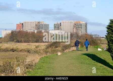 Bradwell Waterside on River Blackwater personnes marchant chien sur le sentier sur le mur de mer avec la centrale nucléaire de Bradwell au-delà de Dengie Peninsula Essex Royaume-Uni Banque D'Images