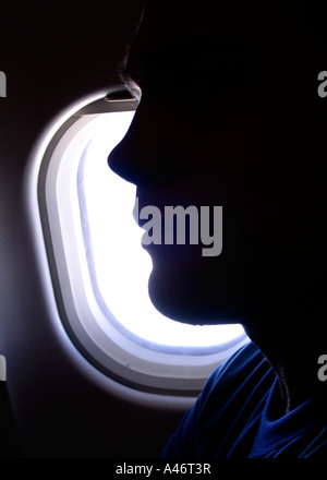 Silhouette de profil du jeune homme en face d'une fenêtre d'avion Banque D'Images