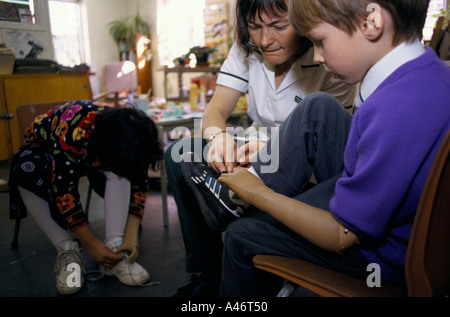 Un physiothérapeute montre un garçon avec une nouvelle prothèse de la main comment déplacer le centre de réadaptation à Roehampton, Londres, UK Banque D'Images