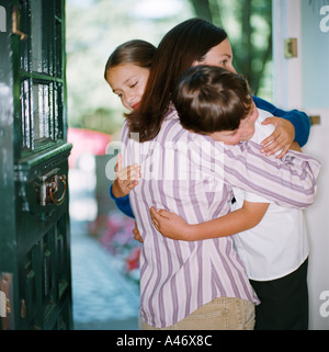 Mother hugging her children in doorway Banque D'Images