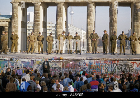 Chute du Mur de Berlin : les gardes-frontière de l'Armée nationale fixant le mur à la porte de Brandebourg, Berlin, Allemagne Banque D'Images