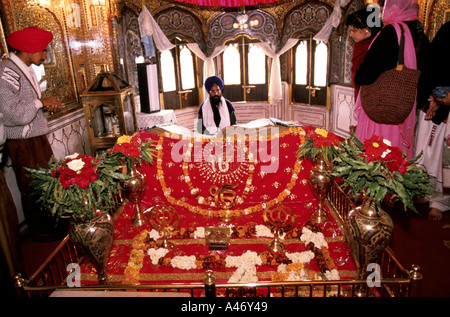 Un homme lit le Shri Guru Granth Sahib, le texte saint des sikhs à l'intérieur du temple d'or à Amritsar, Inde Banque D'Images