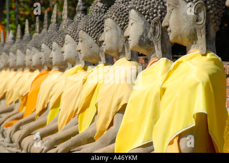 De nombreuses figures de Bouddha dans une rangée avec un chiffon jaune Wat Yai Chai Mongkol Ayutthaya Thaïlande Banque D'Images